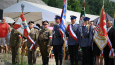 Grupa ludzi w mundurach policyjnych oraz kombatantów stoi ze sztandarami, między innymi sztandar województwa świętokrzyskiego