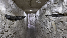 Korytarz podziemnej trasy w rezerwacie. Po bokach ściany z kamieni. Co kilka metrów sztuczne oświetlenie