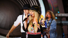 Zdjęcie zbliżenie. Kobieta o długich blond włosach w czarnym kapeluszu. Z mikrofonem śpiewa Maryla Rodowicz