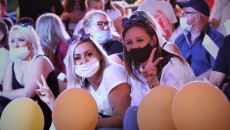 Uśmiechnięte kobiety w maseczkach zakrywających usta i nos podczas zabawy na widowni amfiteatru w Kielcach