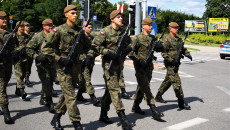 Zdjęcie zbliżenie. Maszerujący żołnierze na ulicach Kielc. W tle radiowóz Policji