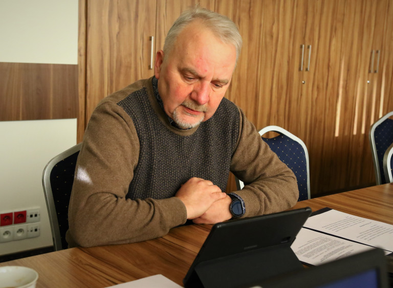 Przewodniczący Komisji Grzegorz Banaś śledzi Prace Radnych Na Monitorze Komputera.
