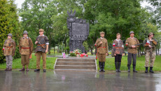 Grupa rekonstrukcyjna stoi przed pomnikiem z napisem Katyń, Charków, Miednoje