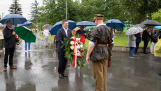 Jacek Włosowicz stoi przed mężczyzną ubranym w strój powstańczy, w rękach trzyma wiązankę kwiatów