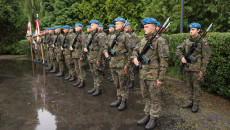 W szeregu stoją mężczyźni w mundurach i niebieskich beretach z bronią na ramionach
