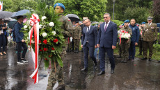 Żołnierz niesie wiązankę kwiatów, za nim idą Tomasz Jamka i Piotr Kisiel