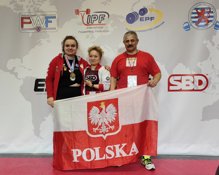 Dwoje Dziewcząt I Trener Stoją Trzymając W Rękach Flagę Polski
